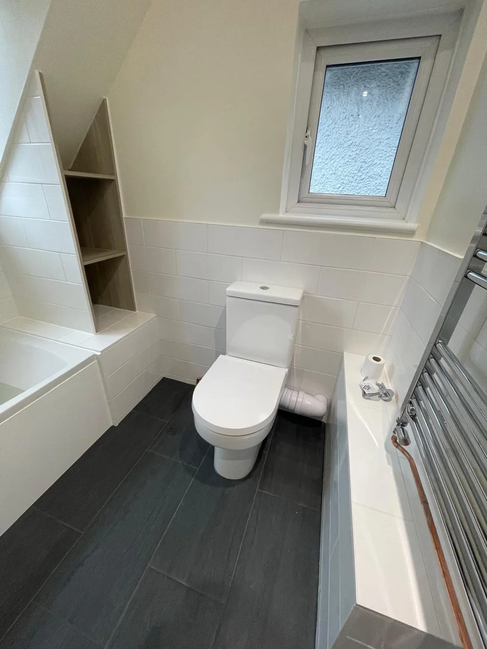 Loft bathroom with metro tiles, bespoke oak shelving and slate floor — bathroom installers