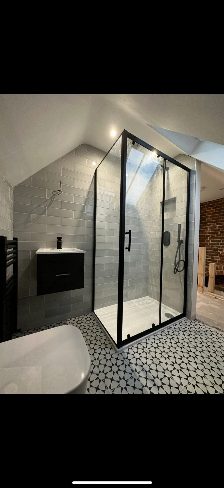 Loft ensuite with matte-black framed shower enclosure and patterned floor