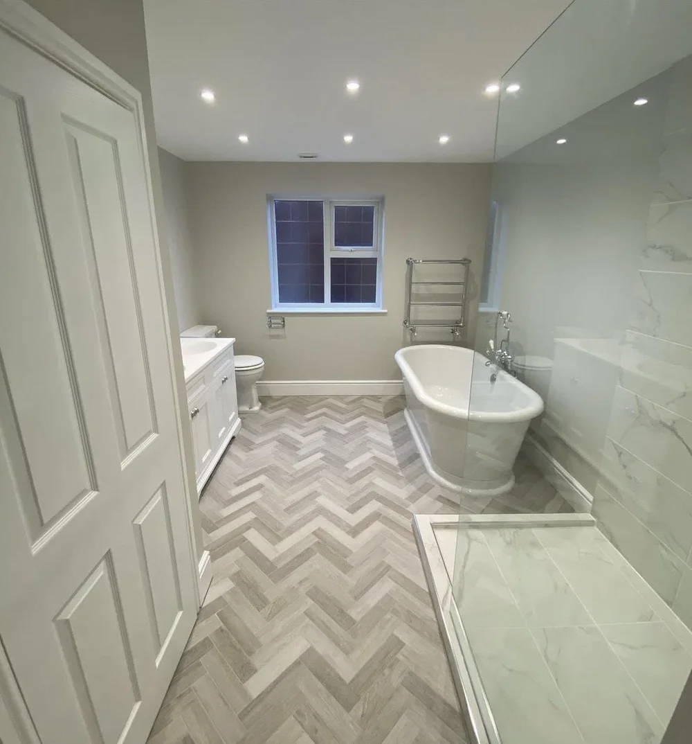 Traditional family bathroom with freestanding roll-top bath, herringbone floor and marble walk-in shower — bathroom installation