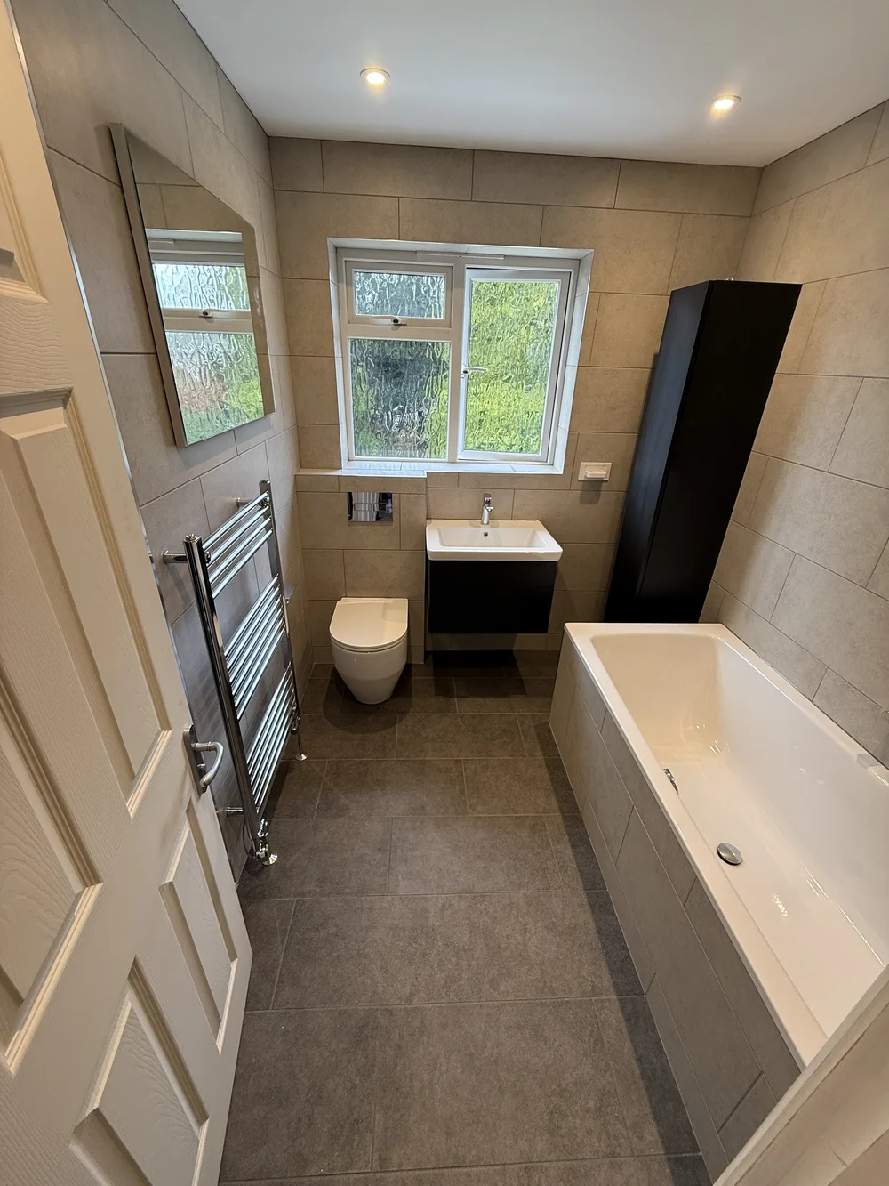 Compact family bathroom with black vanity, wall-hung WC and built-in bath — bathroom installation
