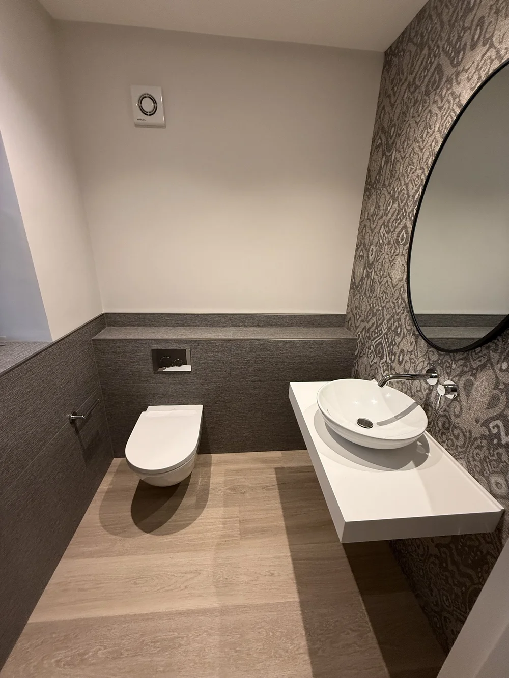 Bespoke cloakroom with patterned wallpaper, oak floor and floating vessel basin